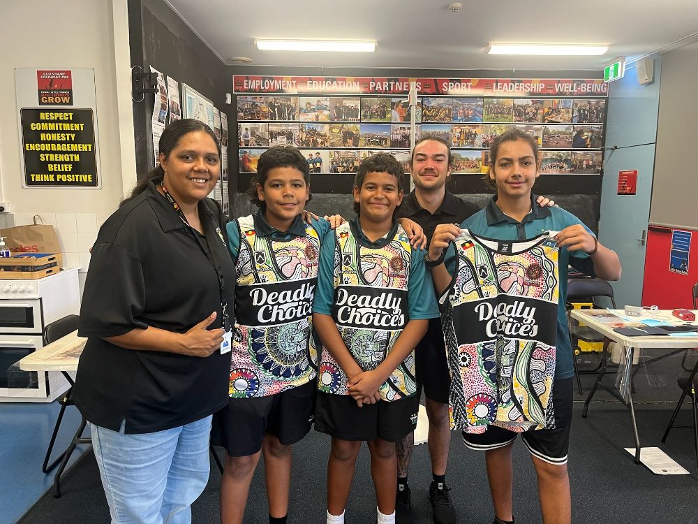 Two Danila Dilba AHPs give Deadly Choices singlets out to three Nightcliff Middle School students after they get their School Based Health Checks. 
