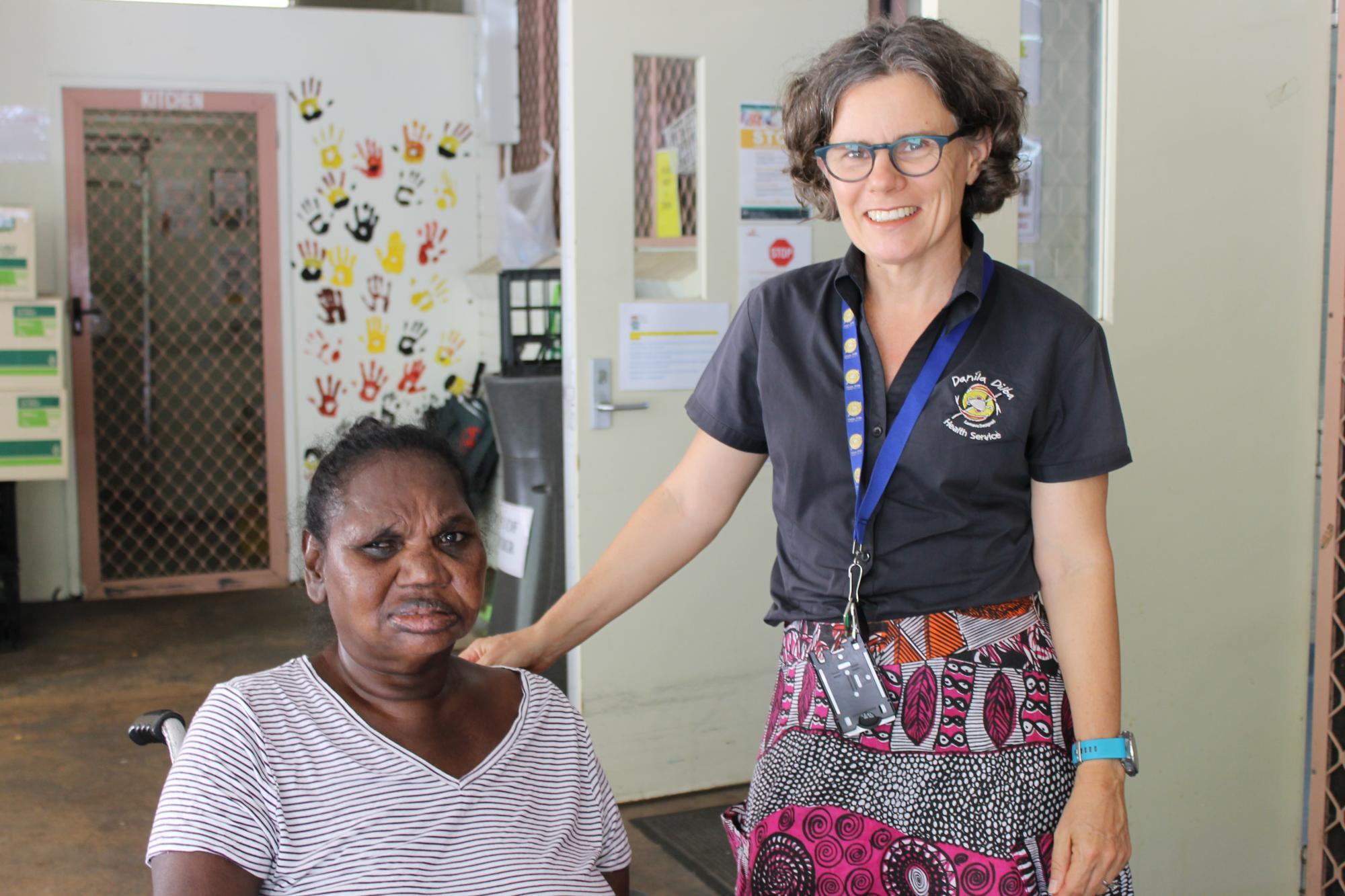 DDHS client meets with GP Emma Fitzsimmons at Rapid Creek Clinic. Emma has her hand on the client's wheelchair. Both people are smiling for the photo. 