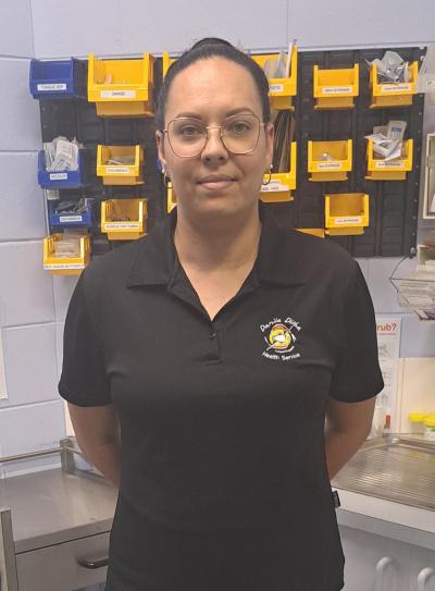 AHP Trainee Cameilla is wearing square wire frame glasses and looking at the camera with a neutral expression. She is wearing a black Danila Dilba polo and has dark hair. 