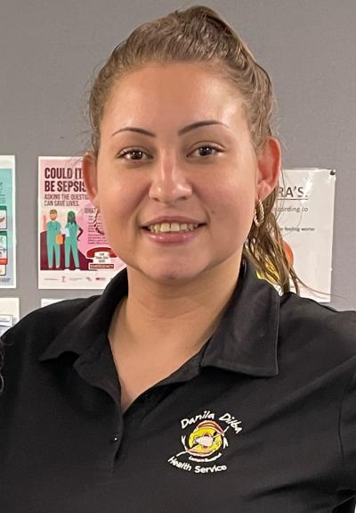 Danila Dilba staff member Casey is smiling at the camera. She has a black polo shirt with the DDHS logo and her hair is in a pony tail.