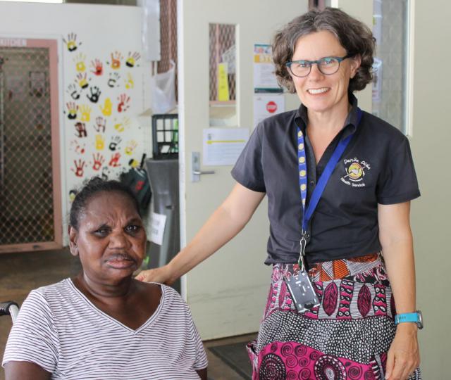 DDHS client meets with GP Emma Fitzsimmons at Rapid Creek Clinic. Emma has her hand on the client's wheelchair. Both people are smiling for the photo. 